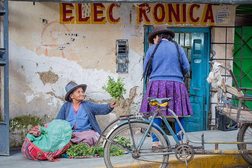 Peruvian women selling herbs on street with bicycle
