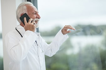 Senior Doctor Talking on Smartphone by Window