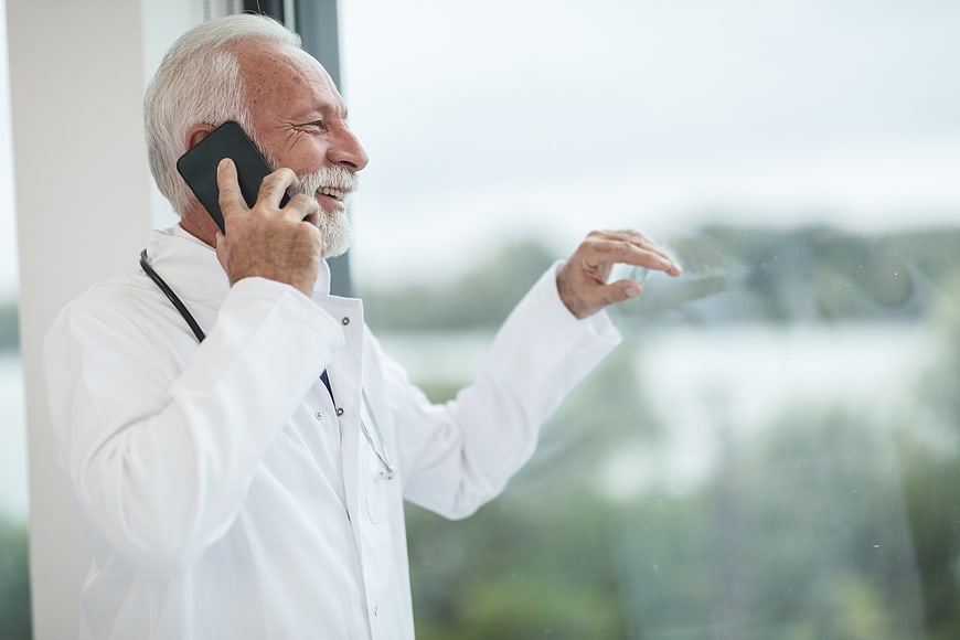 Senior Doctor Talking on Smartphone by Window