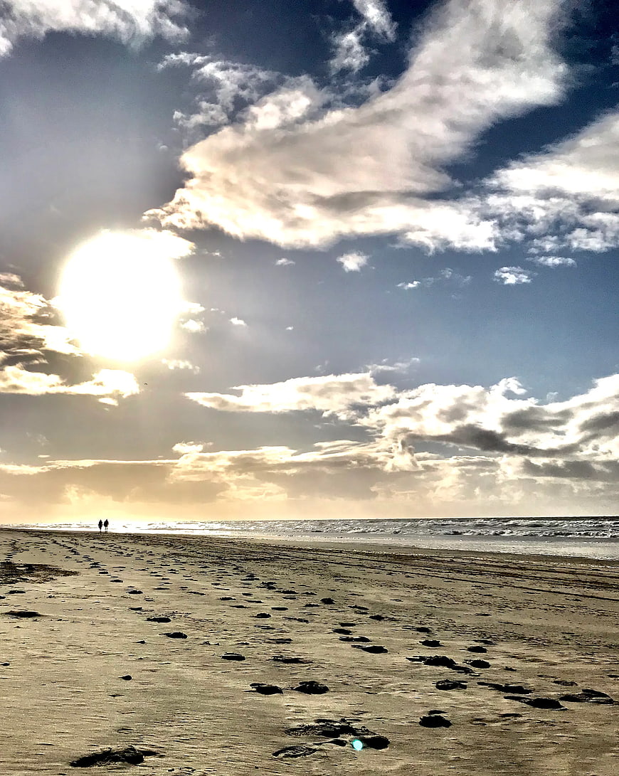 Sunset Beach Landscape with Footprints and Walking Couple