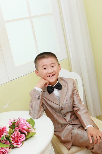 Young boy in formal suit and bow tie smiling in studio