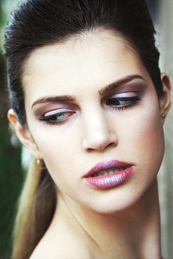 Close-up portrait of a woman with bold makeup looking away
