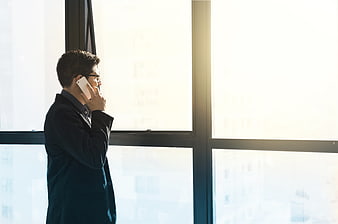 Businessman on phone by window with city view
