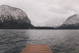 Wooden dock on lake with snowy mountains and fog