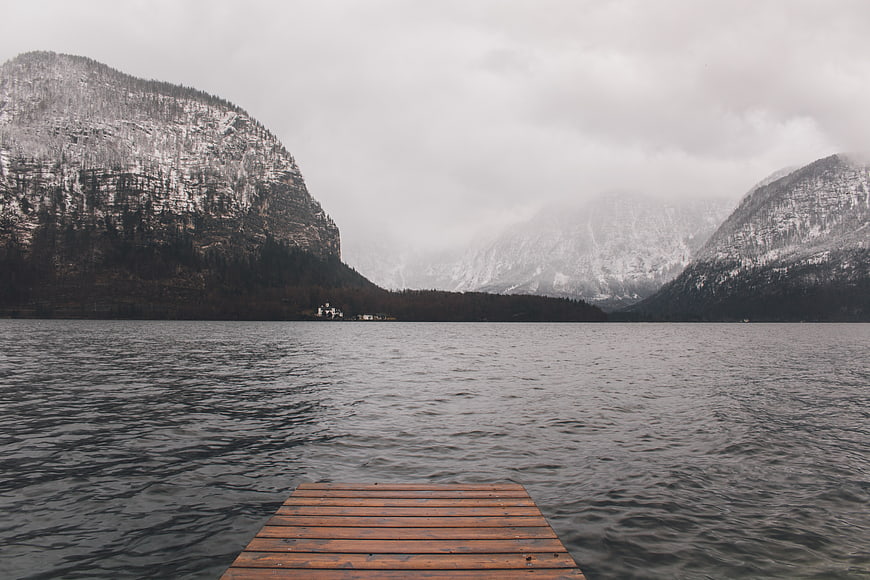 Wooden dock on lake with snowy mountains and fog