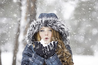 Woman Blowing Snow from Hands in Winter Forest