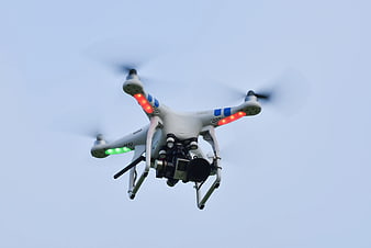 White DJI Phantom drone flying against blue sky