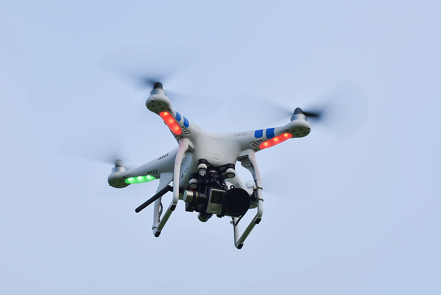 White DJI Phantom drone flying against blue sky