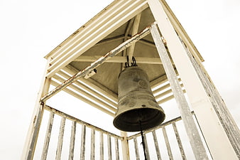 Low angle view of weathered bell in white wooden tower