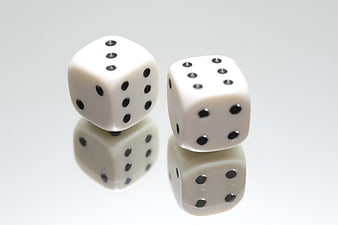 Two white dice on a reflective white background