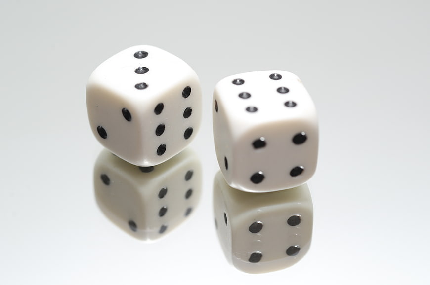 Two white dice on a reflective white background