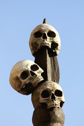 Stacked Skull Sculpture Against Blue Sky