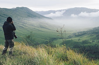 Photographer Capturing Misty Mountain Valley Panorama in Indonesia