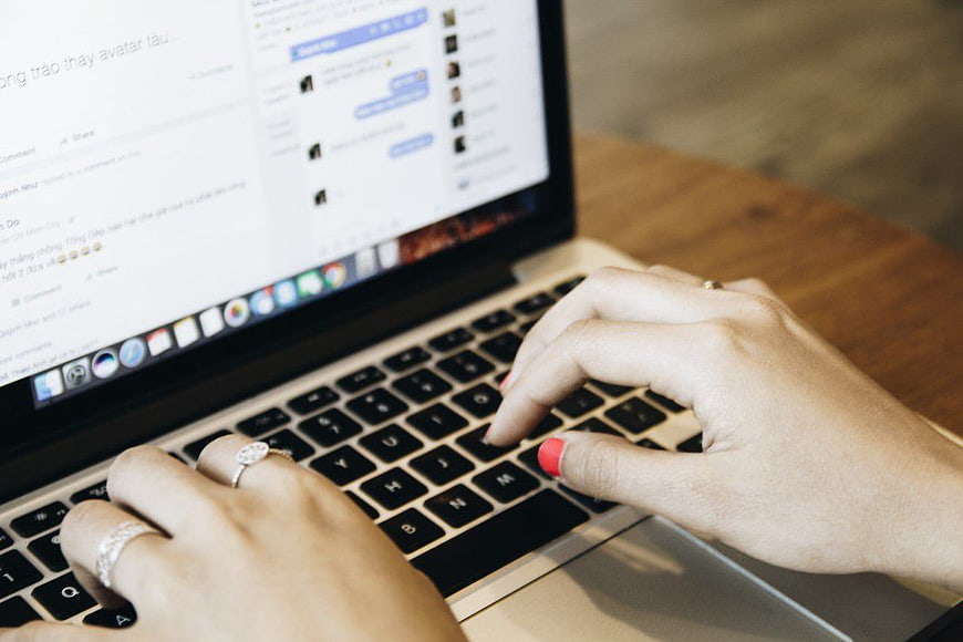 Close-up of hands typing on a laptop keyboard