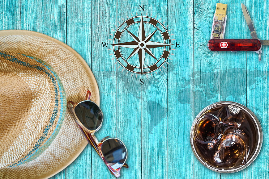 Summer travel essentials on turquoise wooden background