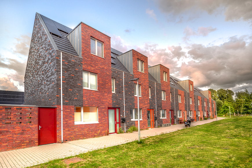 Modern brick row houses with red doors and solar panels