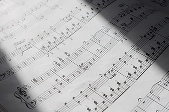 Close-up of classical piano sheet music with dramatic diagonal shadow