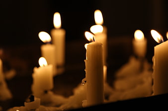 Close-up of lit white candles in the dark