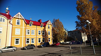 Yellow apartment building with red roof on sunny autumn day