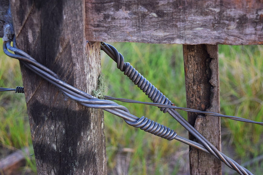Close-up of twisted wire fence on weathered wooden post