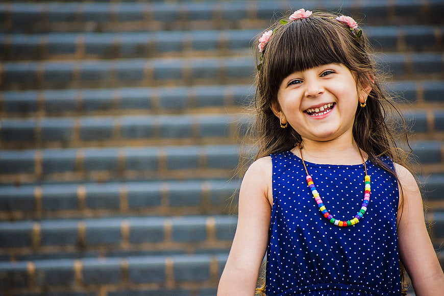Smiling young girl with flower crown and colorful beaded necklace outdoors