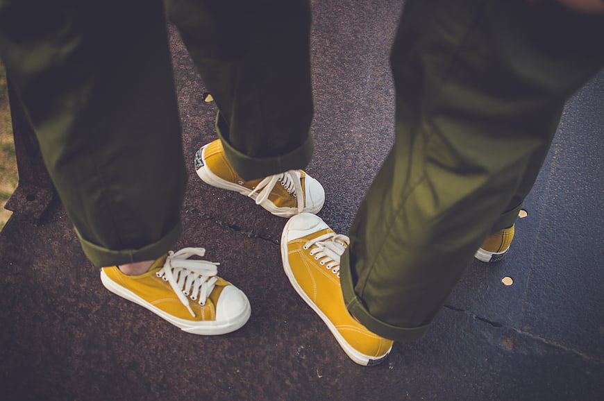 Close-up of yellow sneakers and green pants on pavement