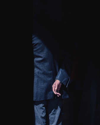 Senior man in blue coat standing in shadows