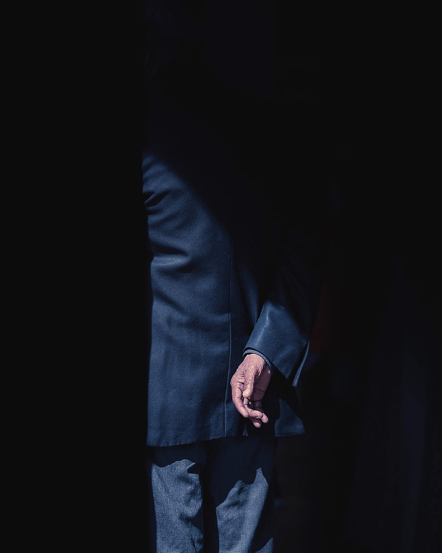 Senior man in blue coat standing in shadows