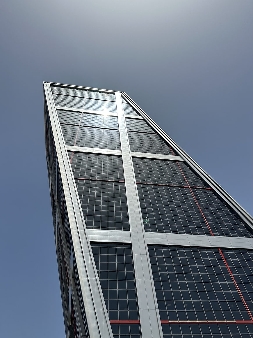 Low angle view of modern glass skyscraper against blue sky