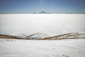 Snowy mountain landscape above sea of clouds