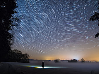 Star Trails Over Misty Landscape With Silhouette