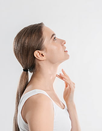 Side profile of woman touching neck against white background