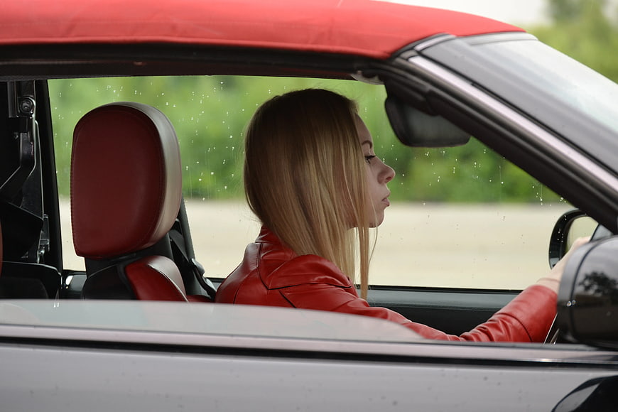 Woman in Red Jacket Driving White Convertible