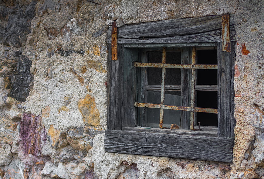 Weathered rustic window in old stone wall