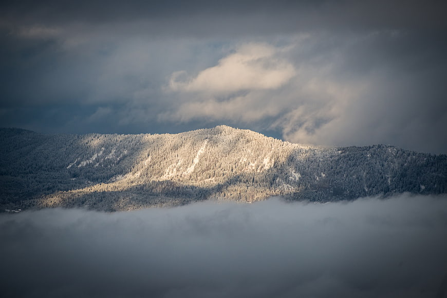 Snow-Capped Mountain Peak Emerging Through Thick Fog and Clouds