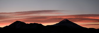 Silhouetted mountain peaks against a vibrant sunset sky