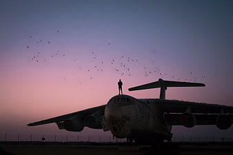 Silhouette of Person Standing on Airplane Nose at Sunset