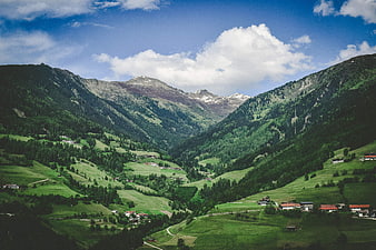 Scenic Alpine Valley with Green Hills and Mountain Peaks