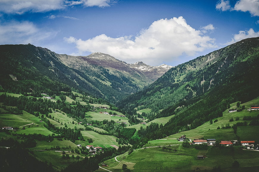 Scenic Alpine Valley with Green Hills and Mountain Peaks