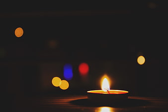Single lit tea light candle with colorful bokeh background