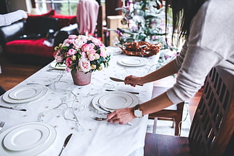 Woman Setting Elegant Christmas Dinner Table with Pink Flowers