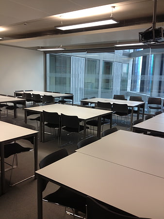 Empty modern classroom with white tables and black chairs