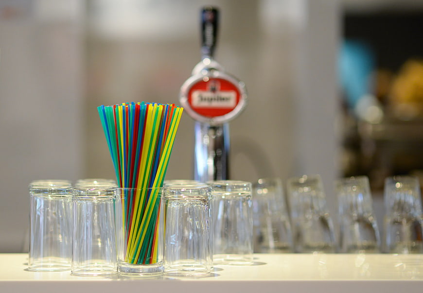 Colorful Straws in Glass with Beer Tap Background