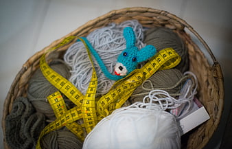 Wicker basket with yarn, measuring tape, and crochet toy