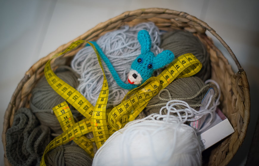 Wicker basket with yarn, measuring tape, and crochet toy