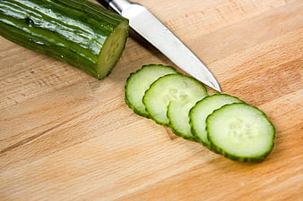 Fresh sliced cucumber on wooden cutting board with knife