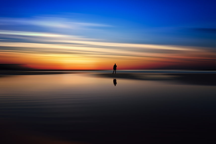 Silhouette of Person Standing on Beach at Sunset
