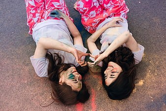 Two women lying on ground with colorful powder celebrating friendship