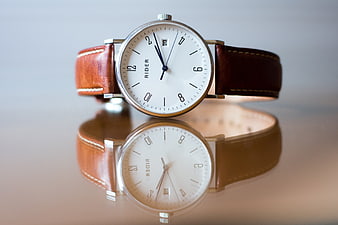 Classic Analog Watch with Brown Leather Strap on Reflective Surface