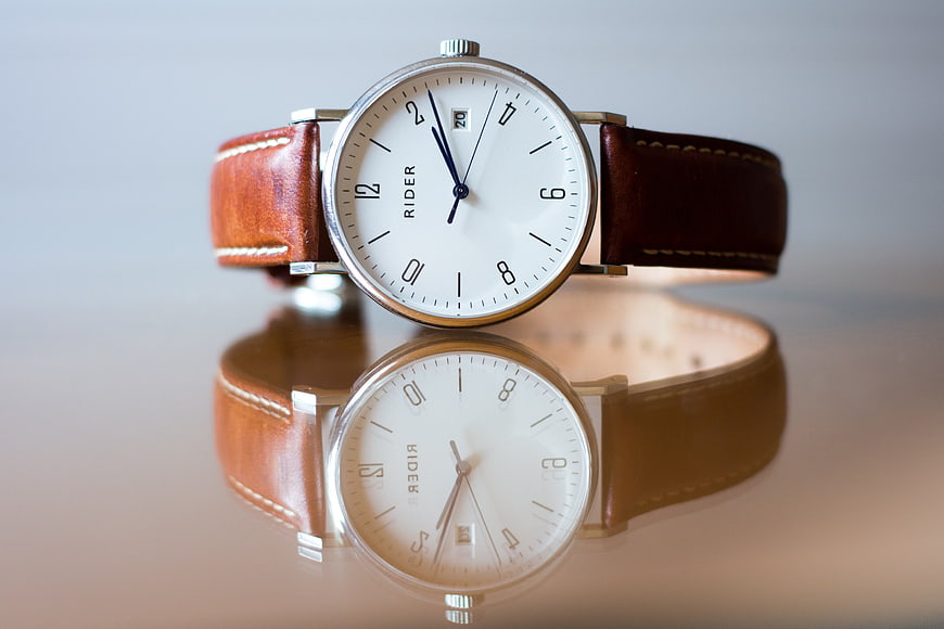 Classic Analog Watch with Brown Leather Strap on Reflective Surface